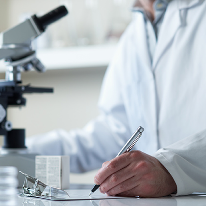 Researcher in a laboratory working with a microscope and taking notes, symbolizing continuous investments in research and development to create innovative and unique products.